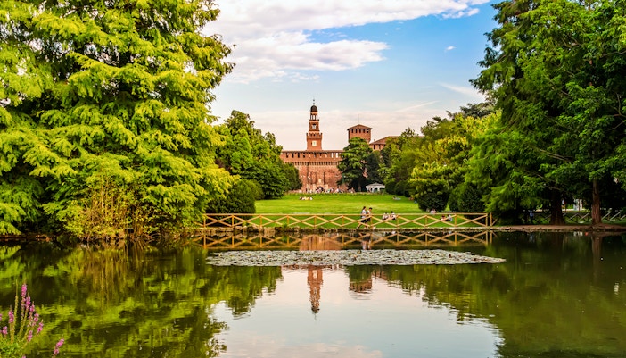 Sforza Castle seen from Parco Sempione, Milan, Italy, with lush greenery in the foreground.