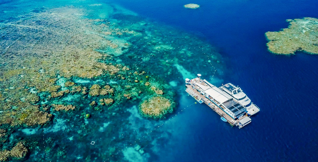 Aerial view of a pontoon at the Great Barrier Reef surrounded by vibrant coral formations.