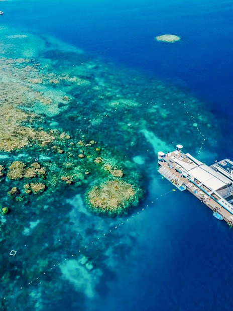 Aerial view of a pontoon at the Great Barrier Reef surrounded by vibrant coral formations.