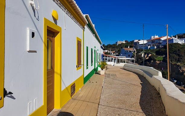Colorful houses along a cobblestone street in Algarve, Portugal.