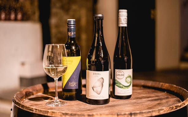 Wine bottles and glass on a barrel in a private wine cellar.