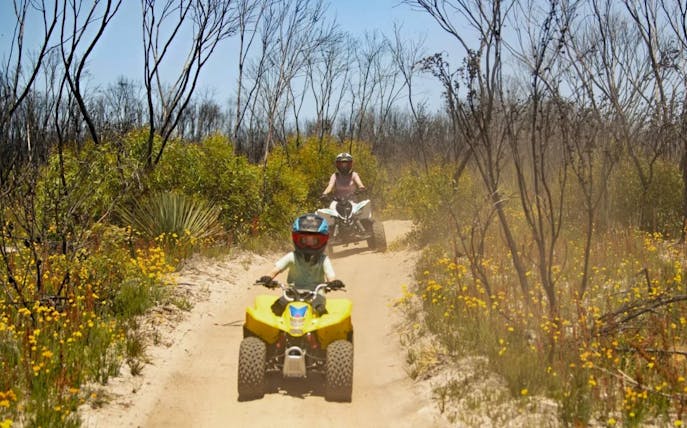 Group riding ATVs through a sandy trail at Vivonne Bay, Kangaroo Island.