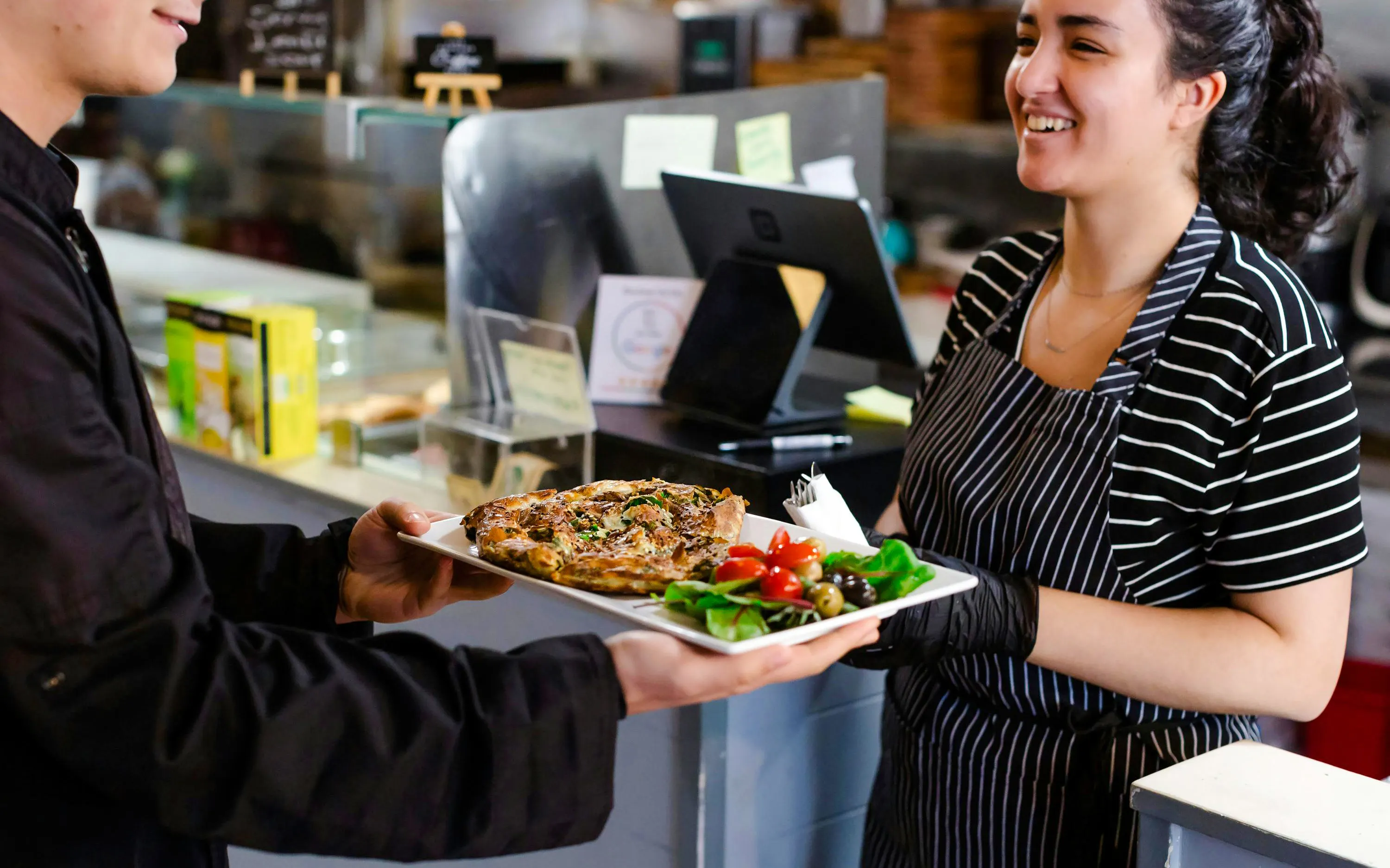 Server presenting a dish with salad and olives during a food tour at Pike Place Market.