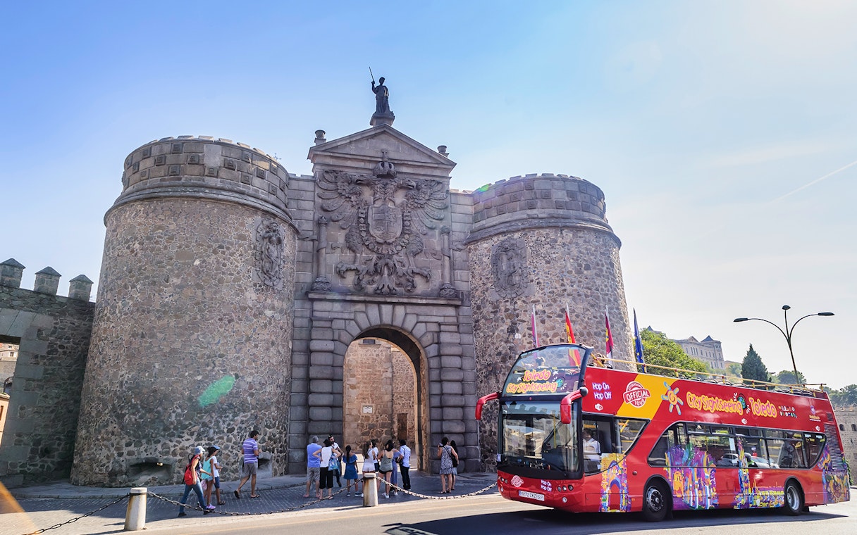 Toledo sightseeing bus in front of Puerta de Bisagra gate.