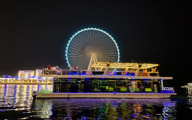 Houseboat on Ain Dubai tour with illuminated Ferris wheel in the background.