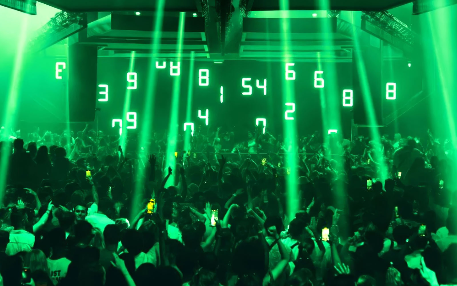 Crowd enjoying Dom Dolla performance with green lights in Ibiza nightclub.
