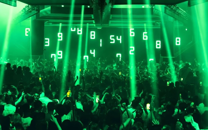 Crowd enjoying Dom Dolla performance with green lights in Ibiza nightclub.