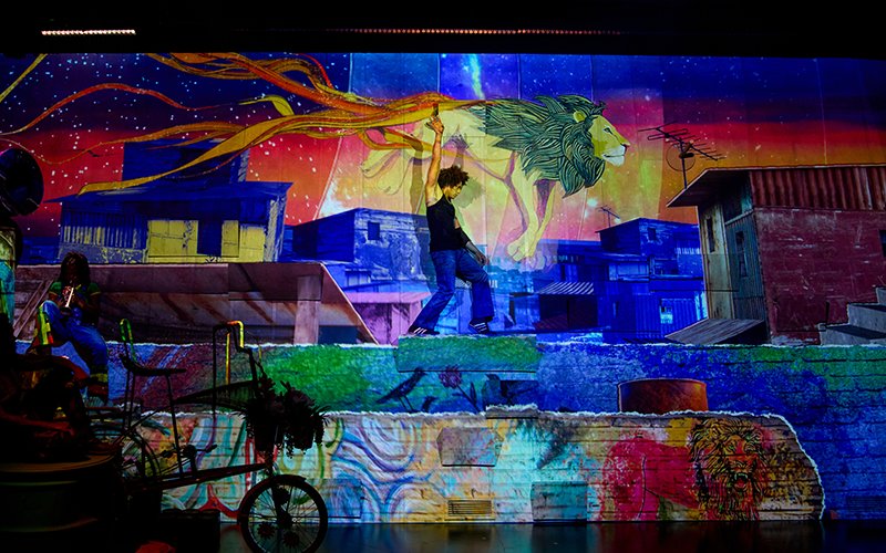 Stage performance at Bob Marley The Show in Vegas with vibrant urban mural backdrop.