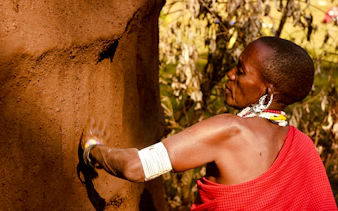 Maasai woman crafting a mud wall in a village, Zanzibar.