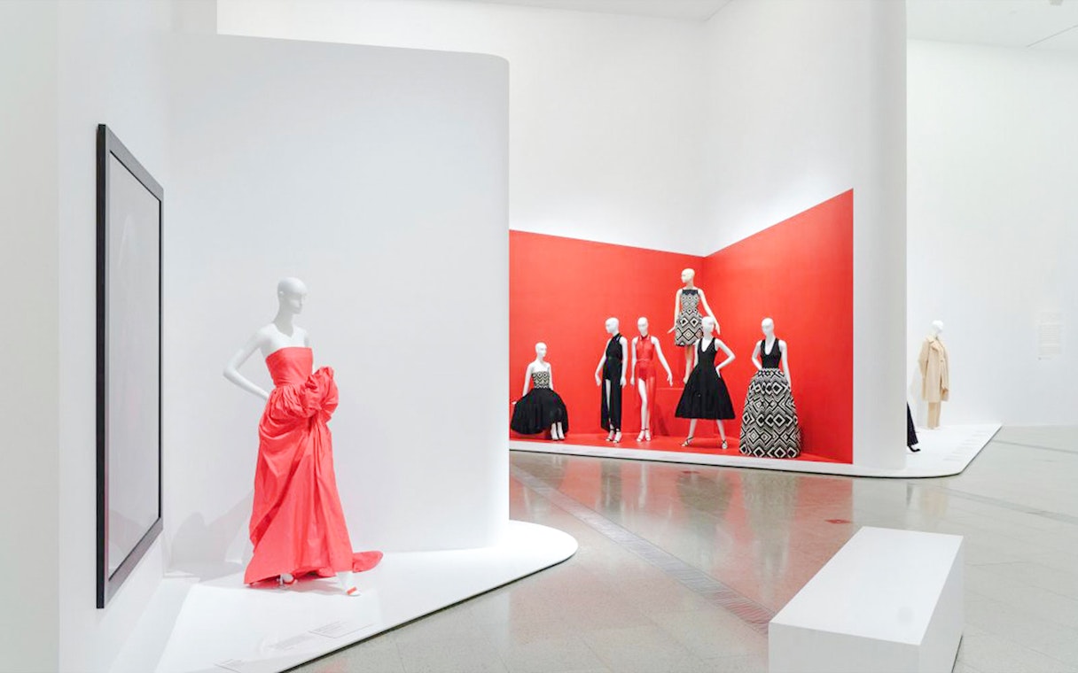 Mannequins displaying Martin Grant designs in a red-themed exhibition space.