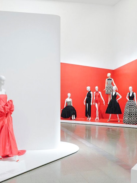 Mannequins displaying Martin Grant designs in a red-themed exhibition space.