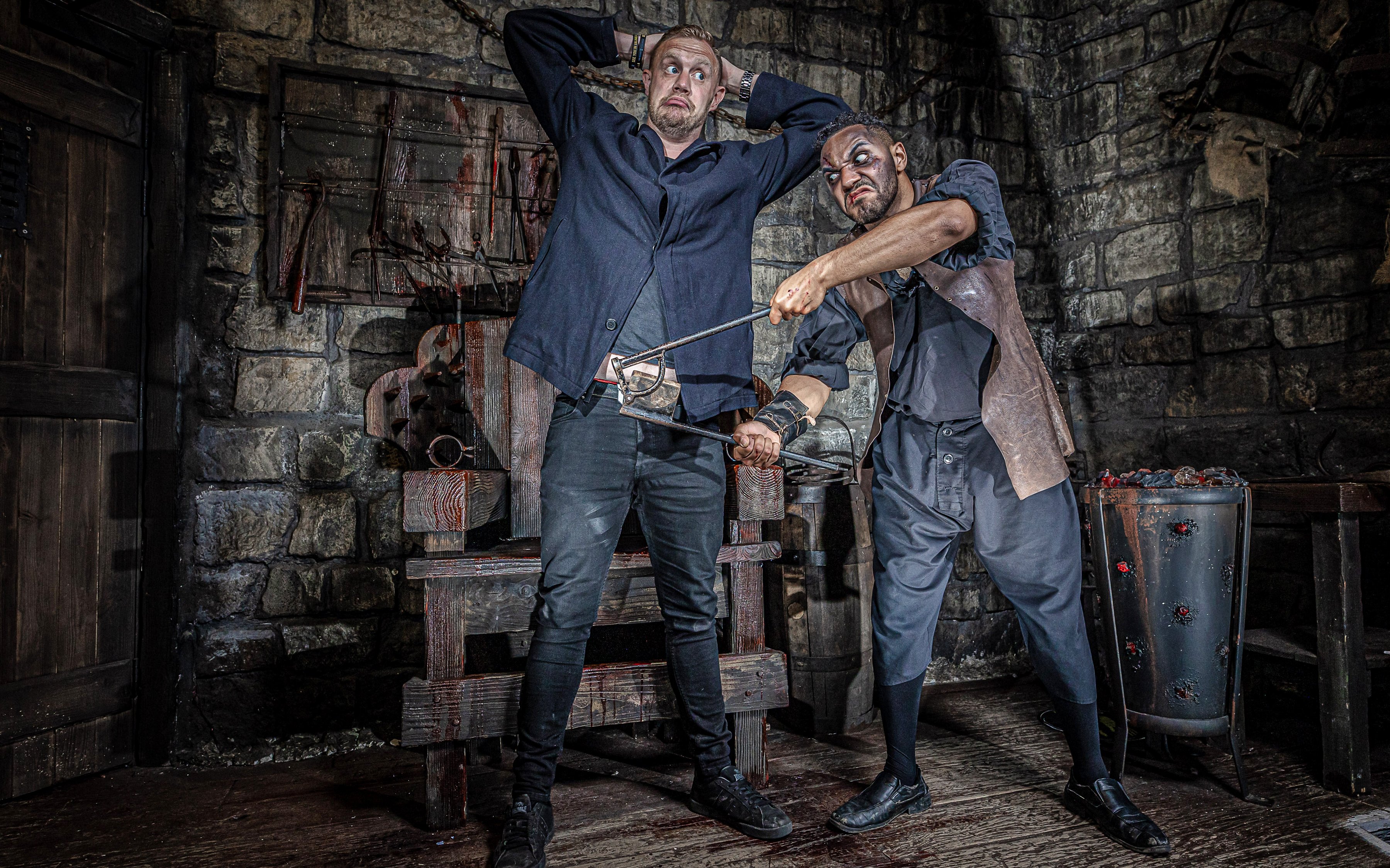 Man in York Dungeon's Torture Chamber with actor holding medieval tool.