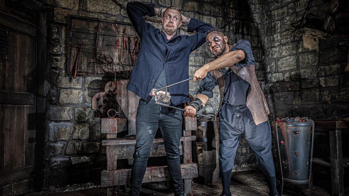 Man in York Dungeon's Torture Chamber with actor holding medieval tool.