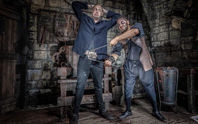 Man in York Dungeon's Torture Chamber with actor holding medieval tool.