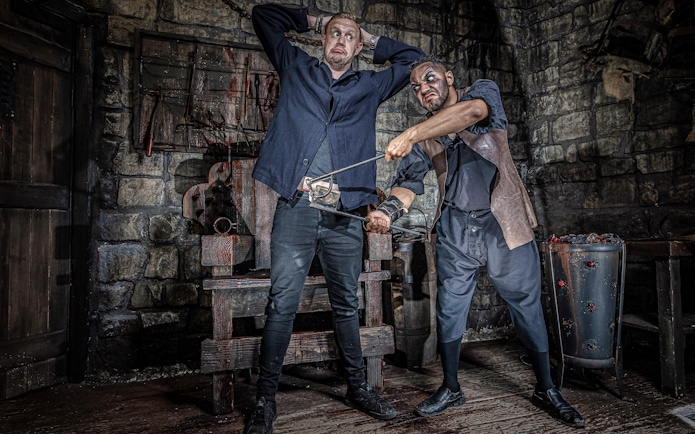 Man in York Dungeon's Torture Chamber with actor holding medieval tool.