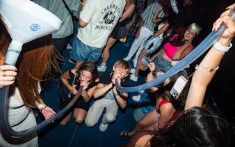 Partygoers enjoying a beer bong on a Split night boat party with a live DJ and free shots.