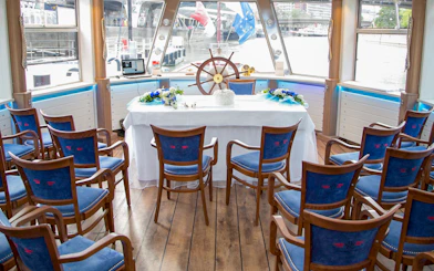 Interior of a Danube Canal cruise ship with arranged seating and a decorated table.