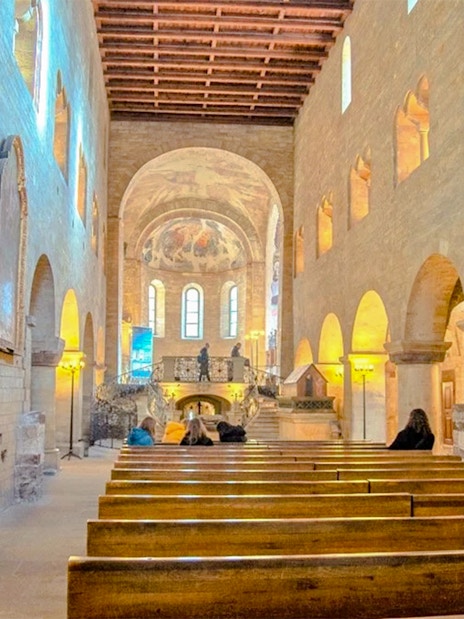 Interior of Basilic of St George with wooden pews and arched windows.