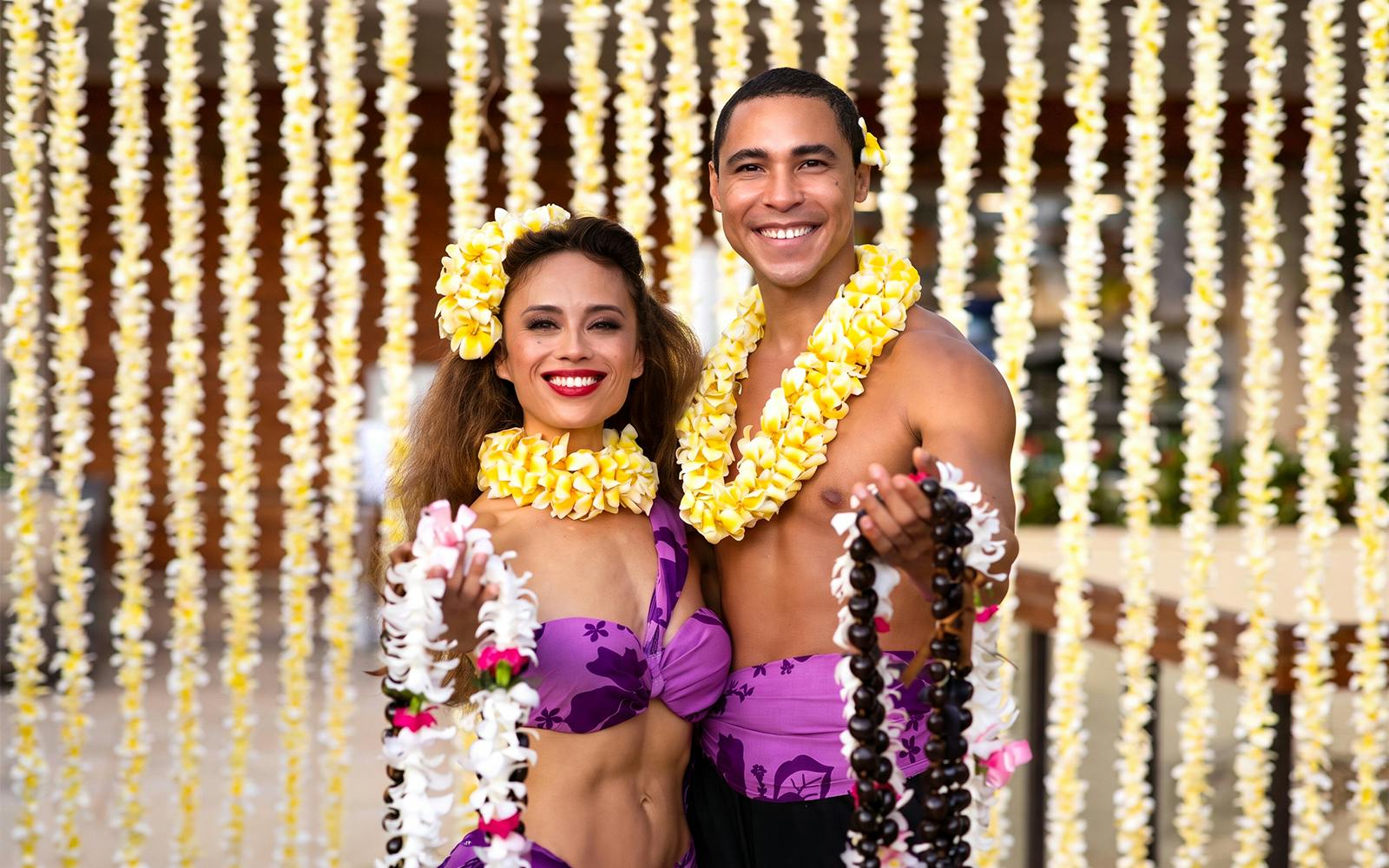 Performers at Na Lei Aloha Luau in Waikīkī wearing traditional Hawaiian attire and flower leis.