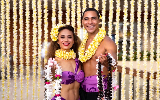 Performers at Na Lei Aloha Luau in Waikīkī wearing traditional Hawaiian attire and flower leis.