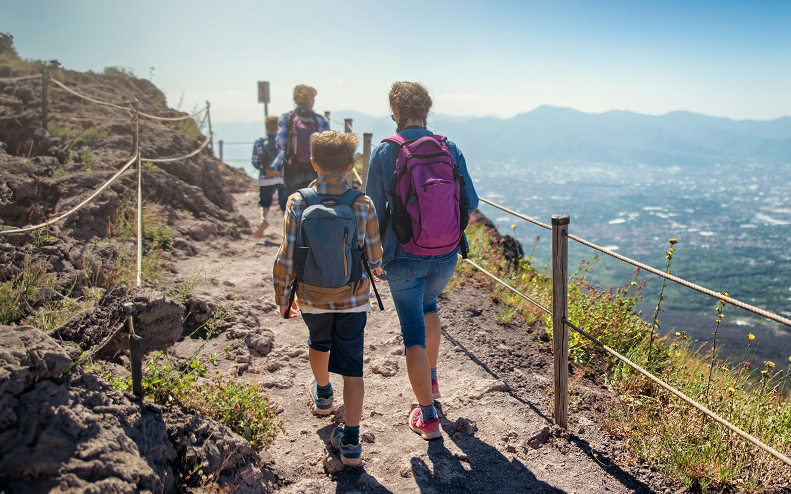 Hikers walking on a trail with views of the landscape on Vesuvius volcano, Italy.