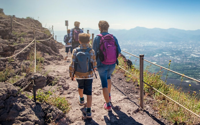 Hikers walking on a trail with views of the landscape on Vesuvius volcano, Italy.
