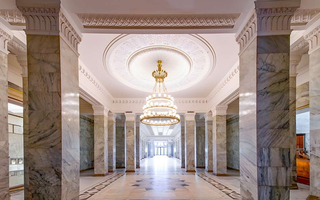 Palace of Culture and Science lobby with marble columns and ornate chandelier.