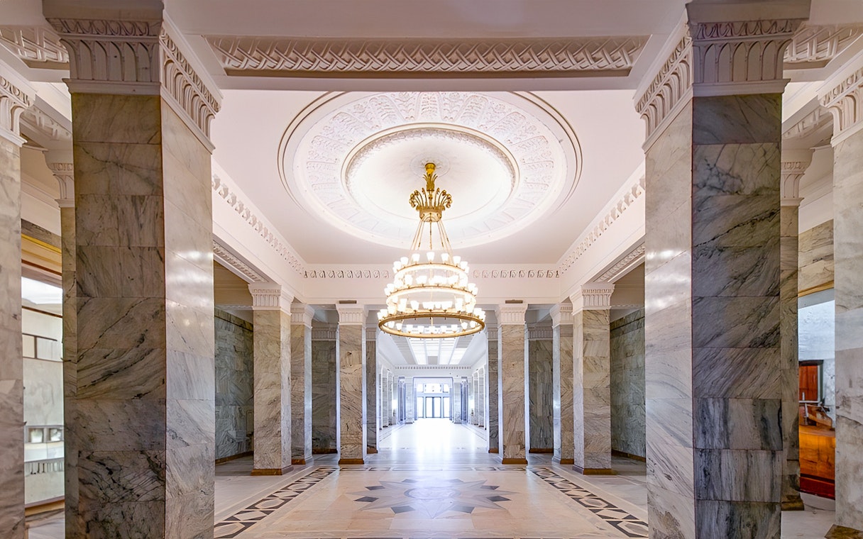 Palace of Culture and Science lobby with marble columns and ornate chandelier.