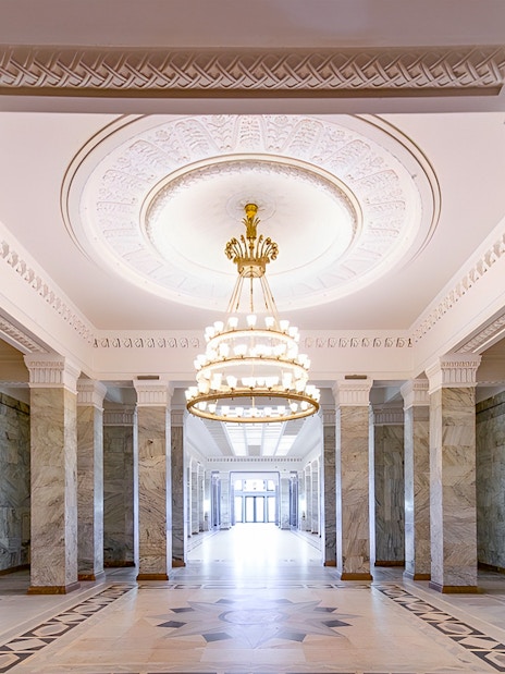 Palace of Culture and Science lobby with marble columns and ornate chandelier.