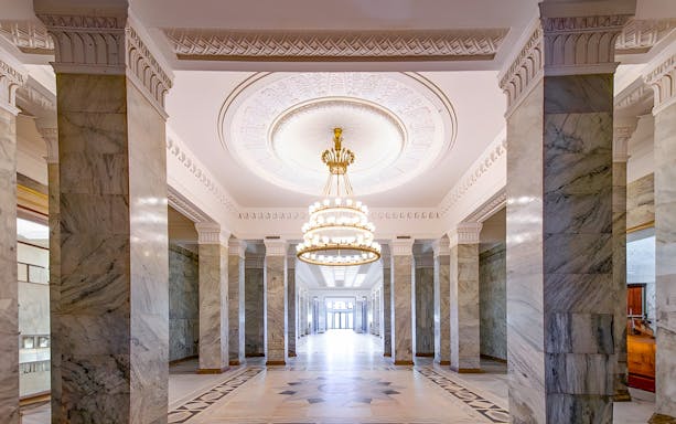 Palace of Culture and Science lobby with marble columns and ornate chandelier.