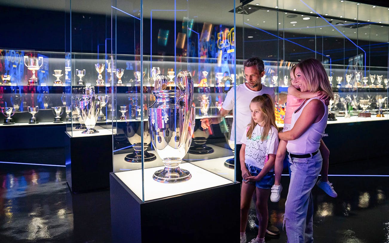 Family viewing Champions League trophy at FC Barcelona museum.