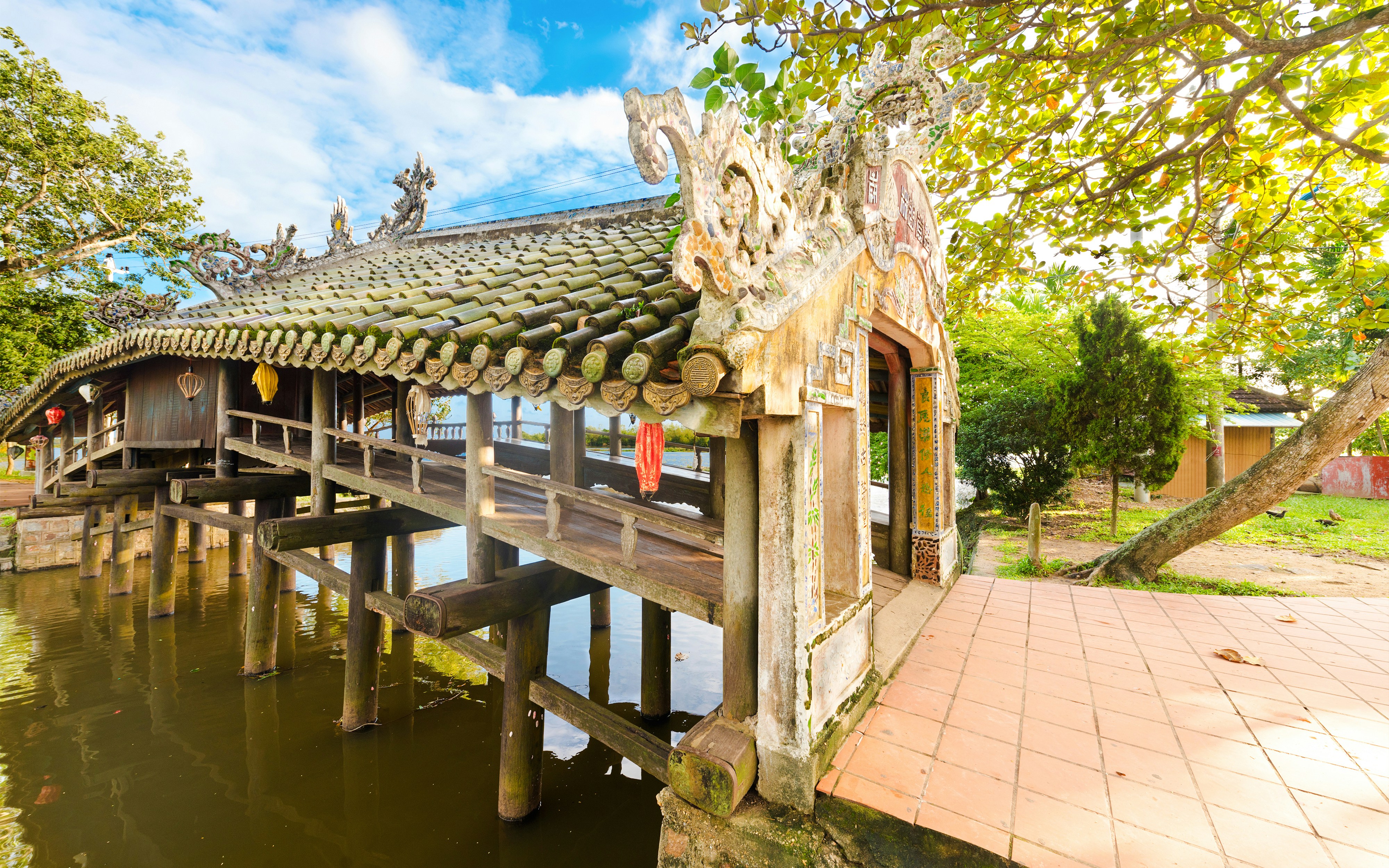 Thanh Toan tile-roofed covered bridge over a serene canal in Vietnam.
