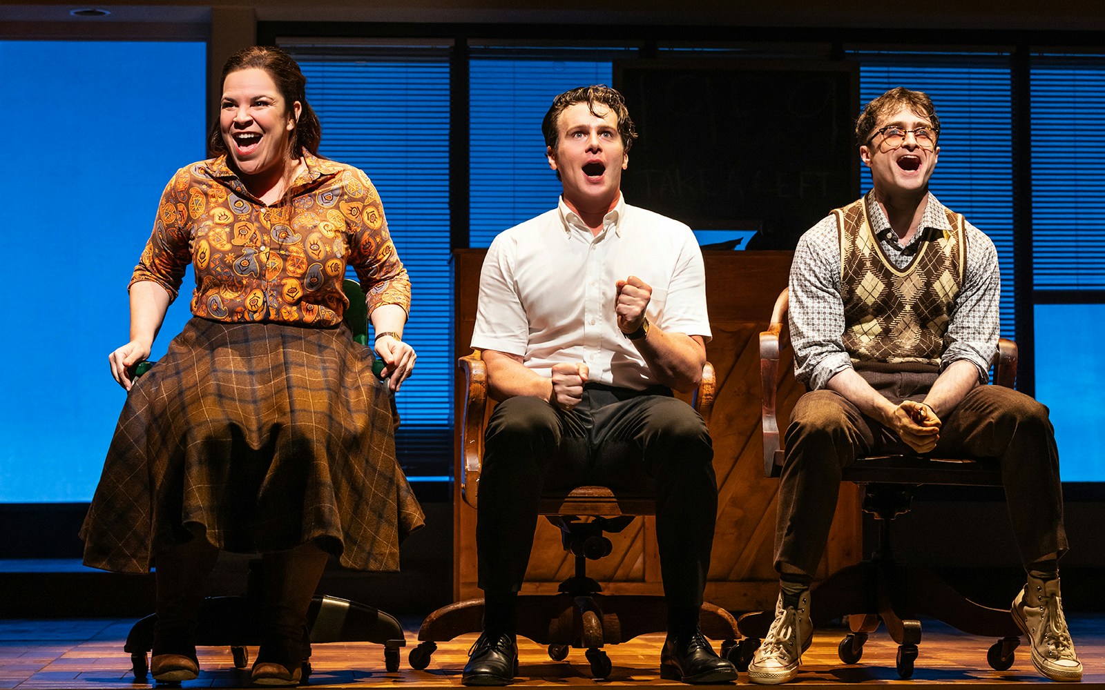Three actors perform a scene from "Merrily We Roll Along" on stage.