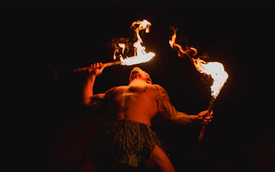 Fire performer at Mauka Warriors Luau holding flaming torches.