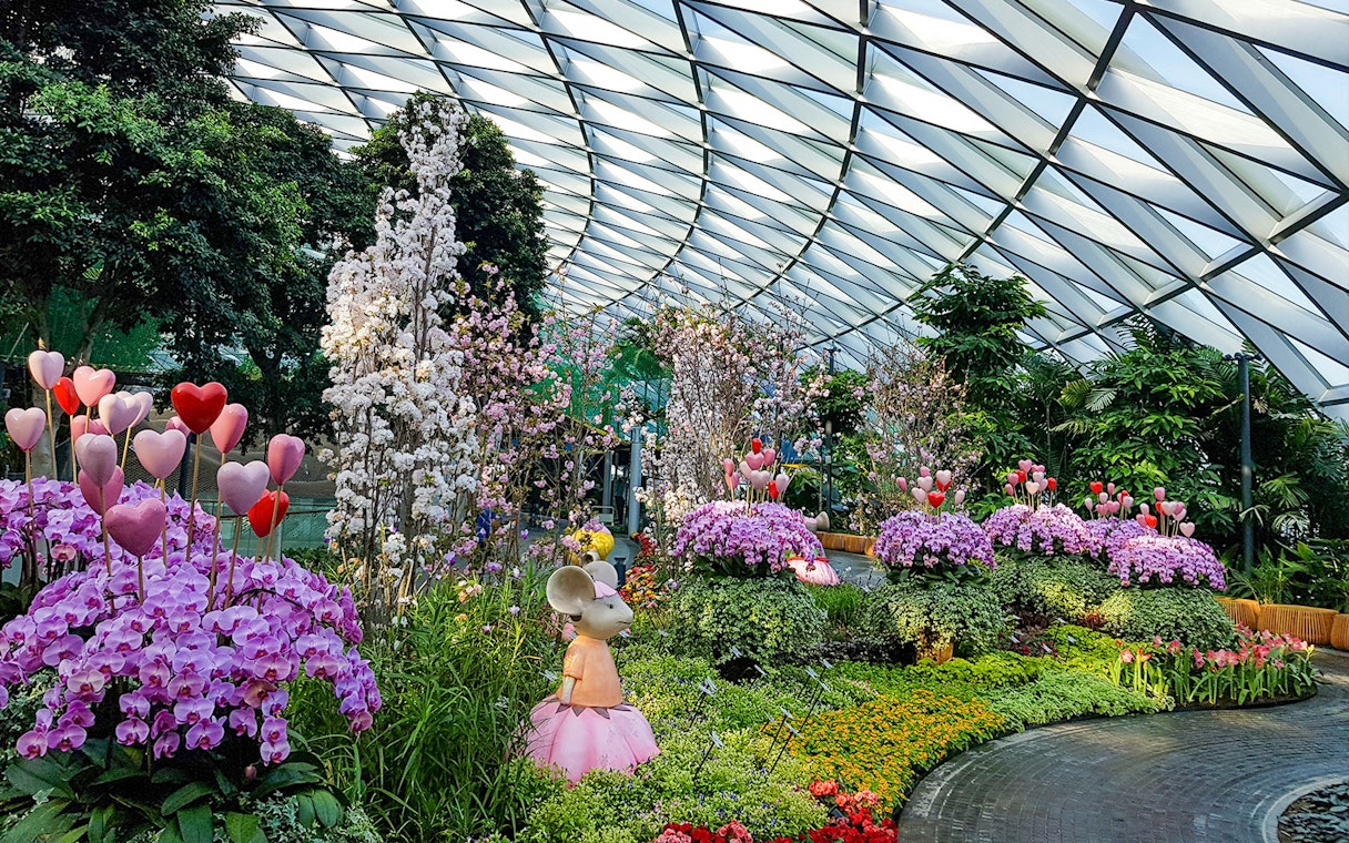Jewel Changi Petal Garden with vibrant flowers and whimsical sculptures under a glass dome.