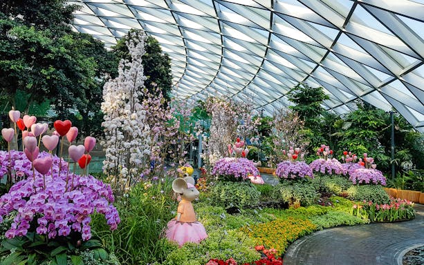 Jewel Changi Petal Garden with vibrant flowers and whimsical sculptures under a glass dome.