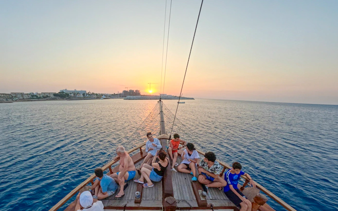 Sunset cruise from Ayia Napa with people relaxing on a boat, overlooking the sea.