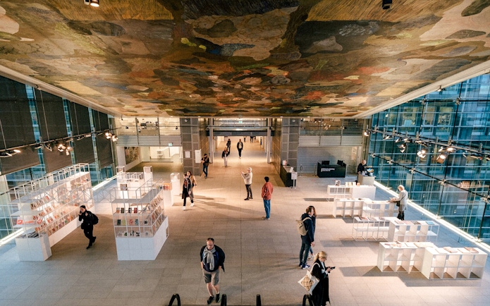Interior of the Black Diamond library in Copenhagen with visitors exploring exhibits.