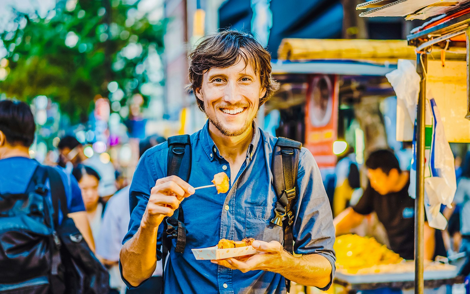 Tourist sampling Korean street food at a bustling Seoul market.