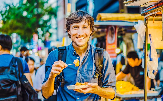 Tourist enjoying street food at a market in Korea.