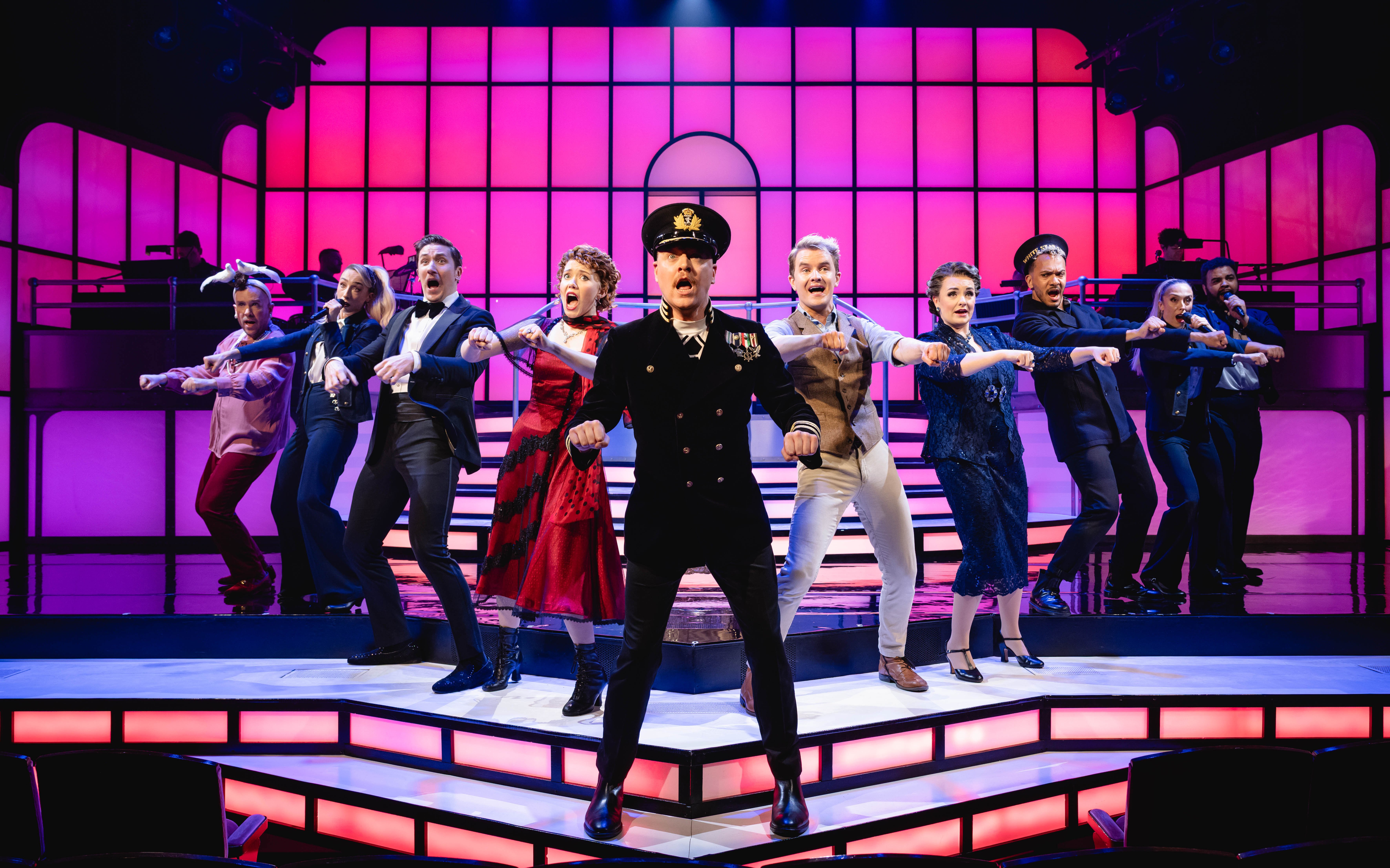 Cast performing a musical number in Titanique Westend with vibrant stage lighting.