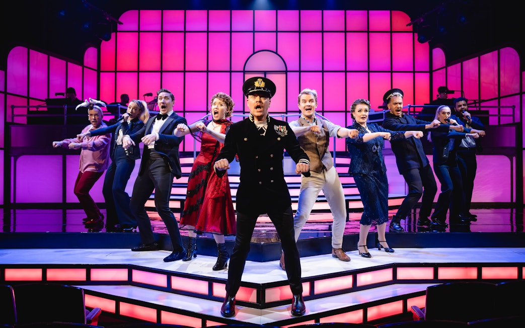 Cast performing a musical number in Titanique Westend with vibrant stage lighting.