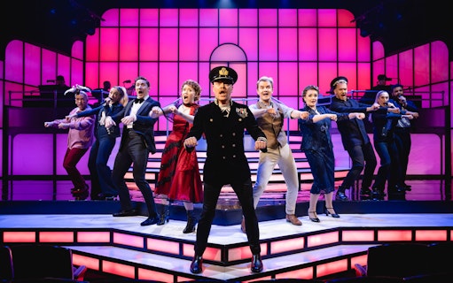 Cast performing a musical number in Titanique Westend with vibrant stage lighting.