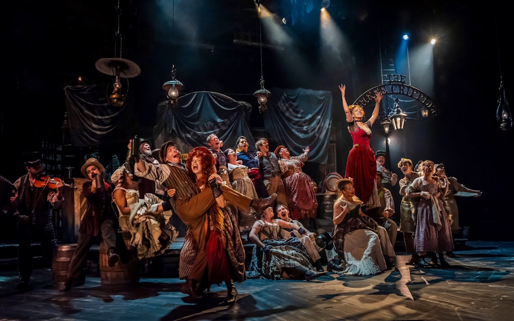 Cast performing a lively scene from the musical "Oliver" on stage.