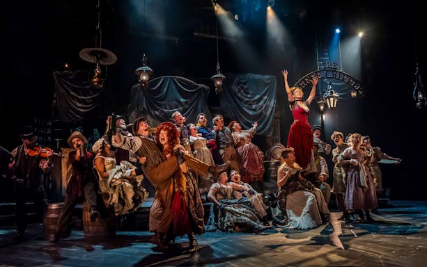 Cast performing a lively scene from the musical "Oliver" on stage.