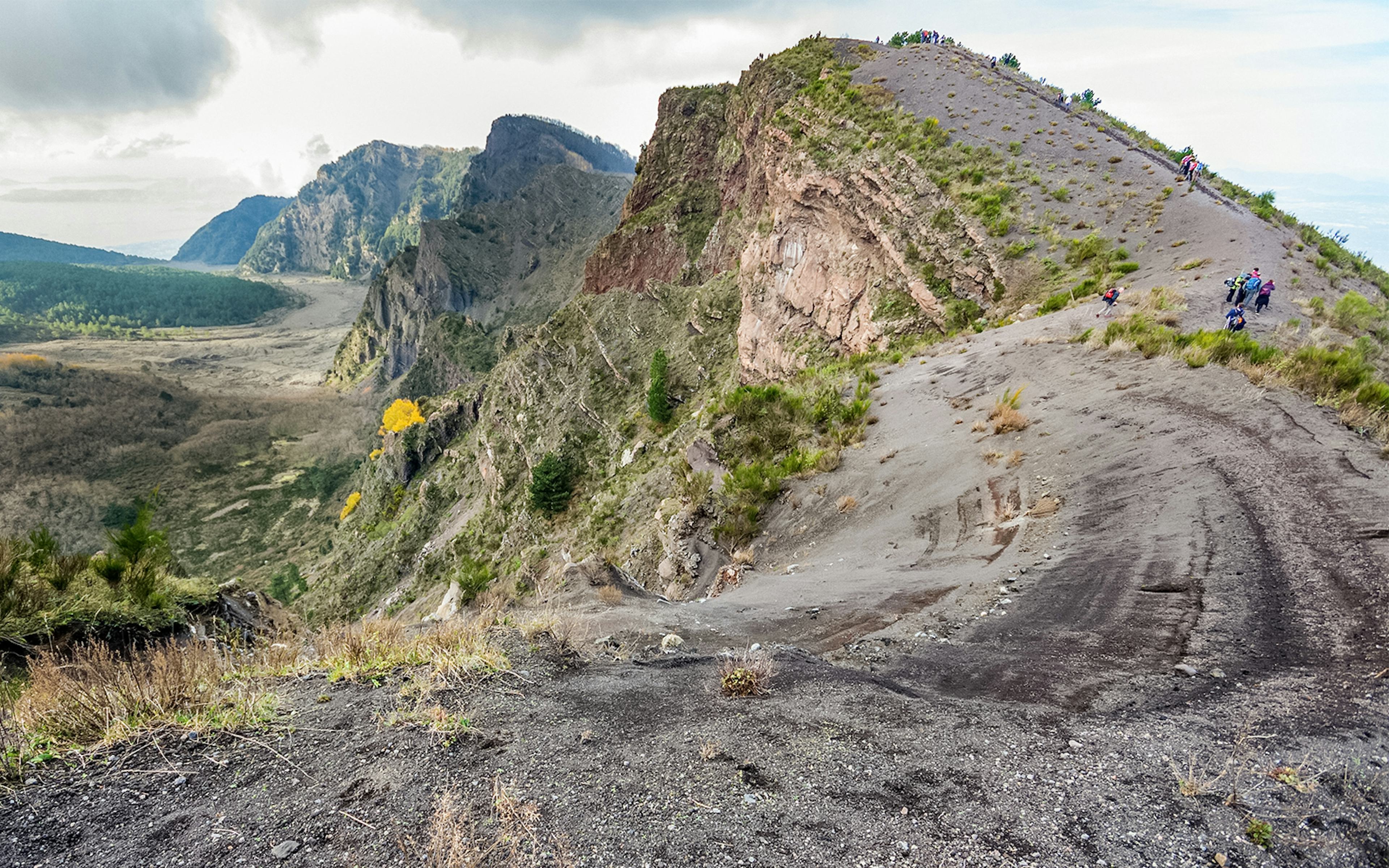 Hikers exploring trails with view of Mount Vesuvius in Vesuvius National Park, Italy.