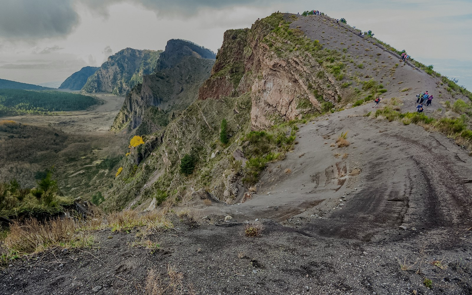Hikers on a trail at Vesuvius National Park with volcanic landscape.
