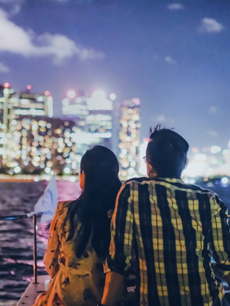 Couple on yacht with Marina Bay Sands and Singapore skyline at night.