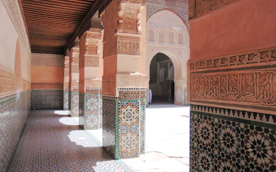 Ben Youssef Madrasa courtyard with intricate tilework and carved arches in Marrakech, Morocco.