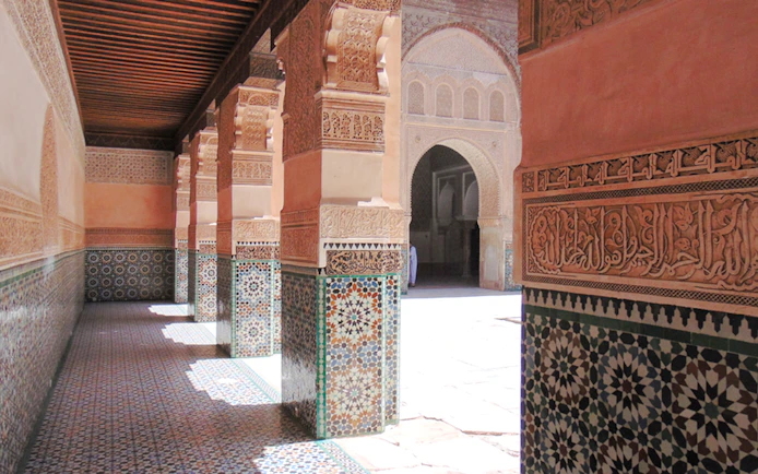 Ben Youssef Madrasa courtyard with intricate tilework and carved arches in Marrakech, Morocco.